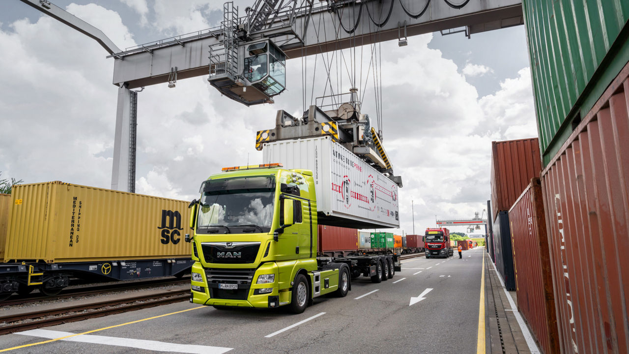 A green MAN truck is loaded with a container