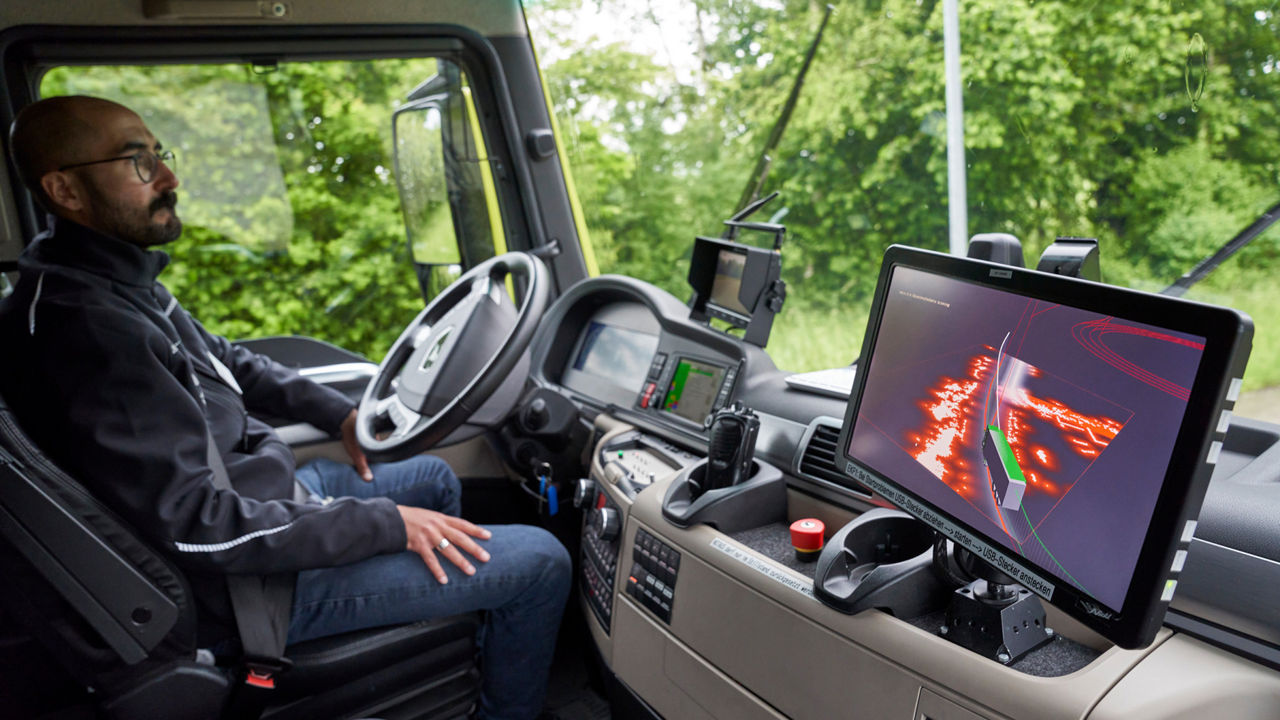 A man sits in a truck in front of screens