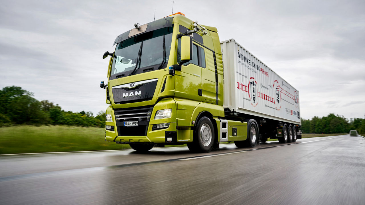 A green MAN truck driving on the road