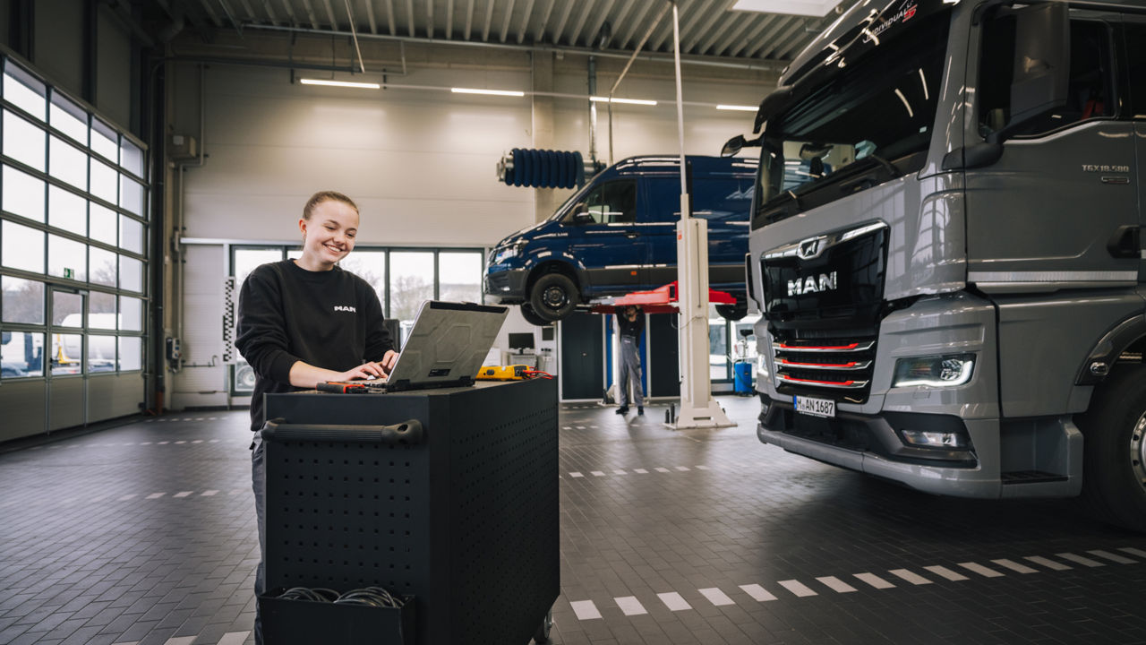 Eine junge Frau arbeitet an einem Laptop neben einem Van
