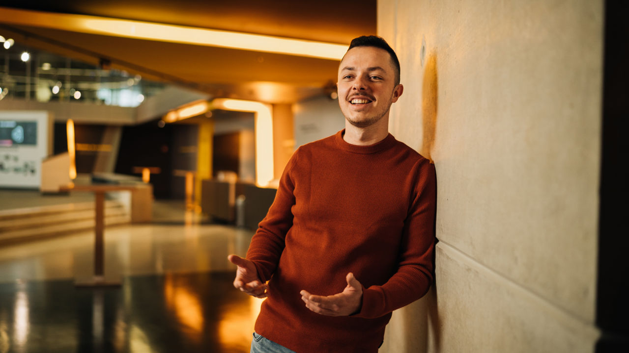 A young man is leaning against a wall
