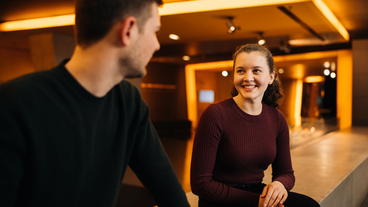 A young woman and young man are talking to each other and laughing