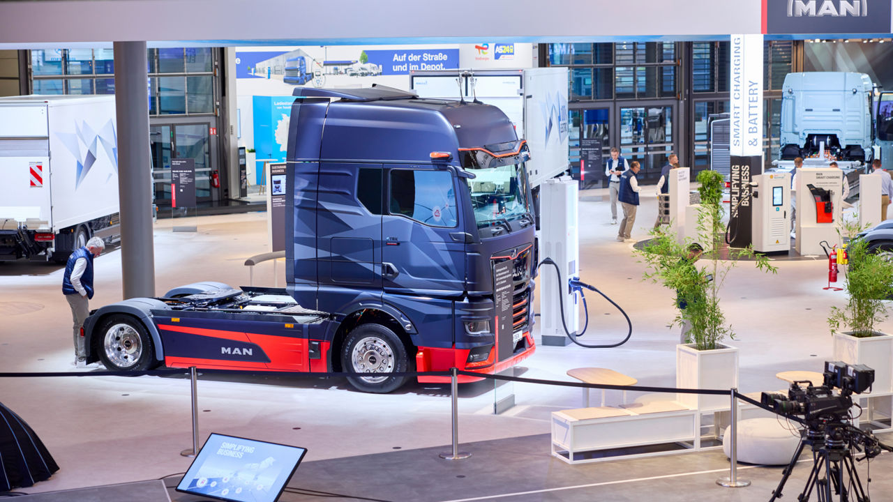 Ein MAN eTGX steht in einer Messehalle und hängt an einer Ladesäule