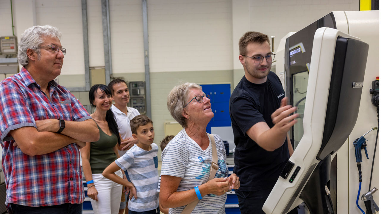Menschen schauen einem Mann zu, wie er eine Maschine bedient