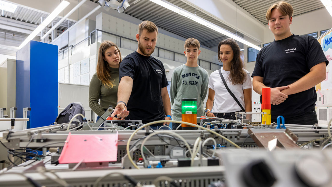 Jugendliche stehen vor einer Maschine mit vielen Kabeln