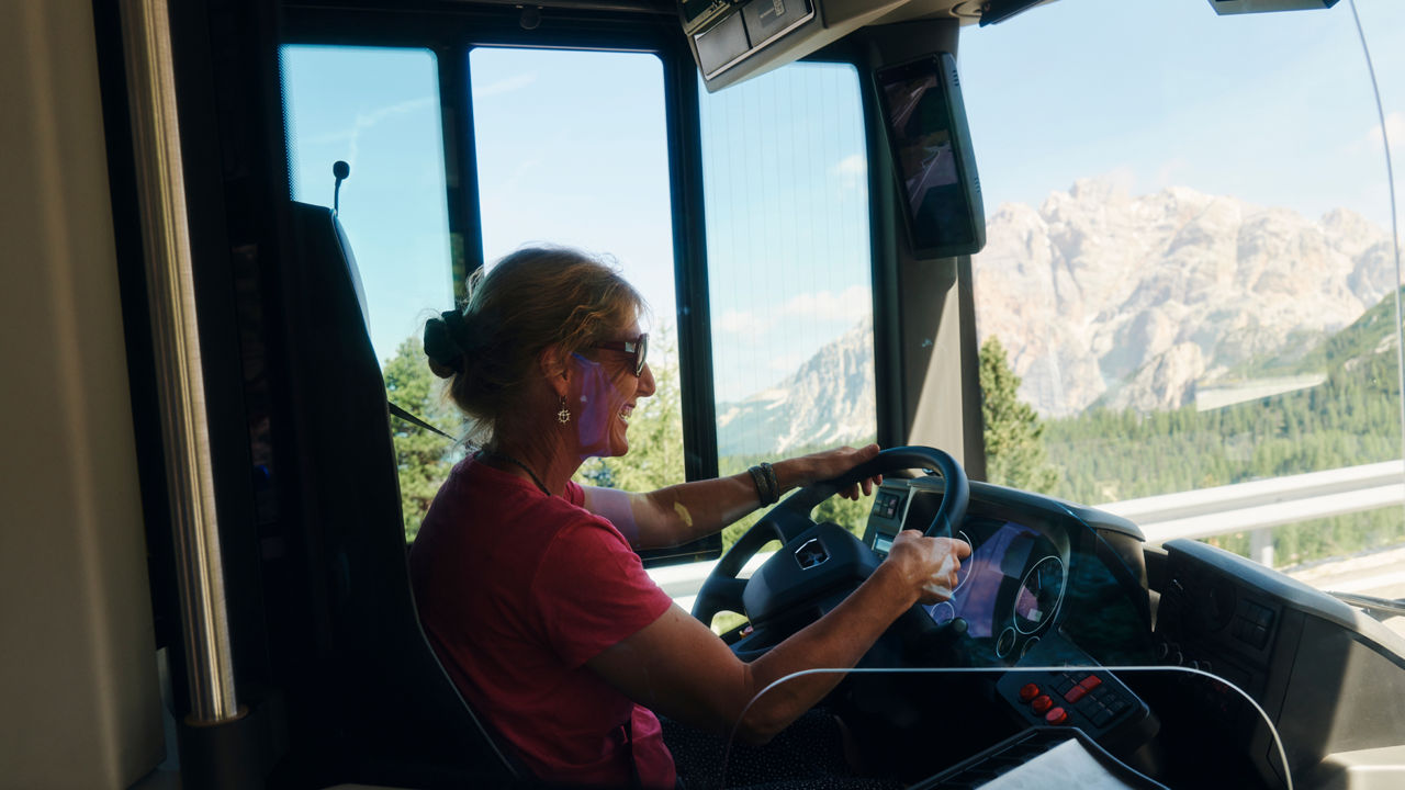 A woman sits at the wheel of a bus