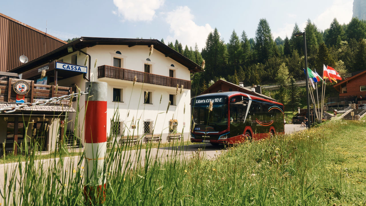 The MAN Lion's City E in front of a house in the mountains