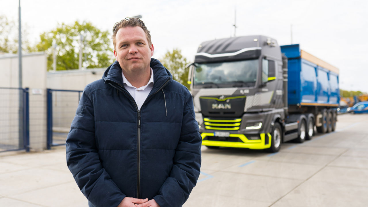 Ein blonder Mann steht vor einem MAN hTGX