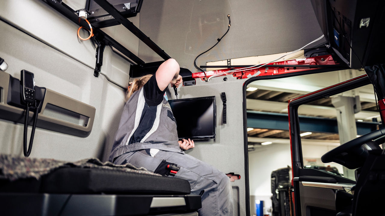 Eine Handwerkerin montiert einen Fernseher im Ruheraum