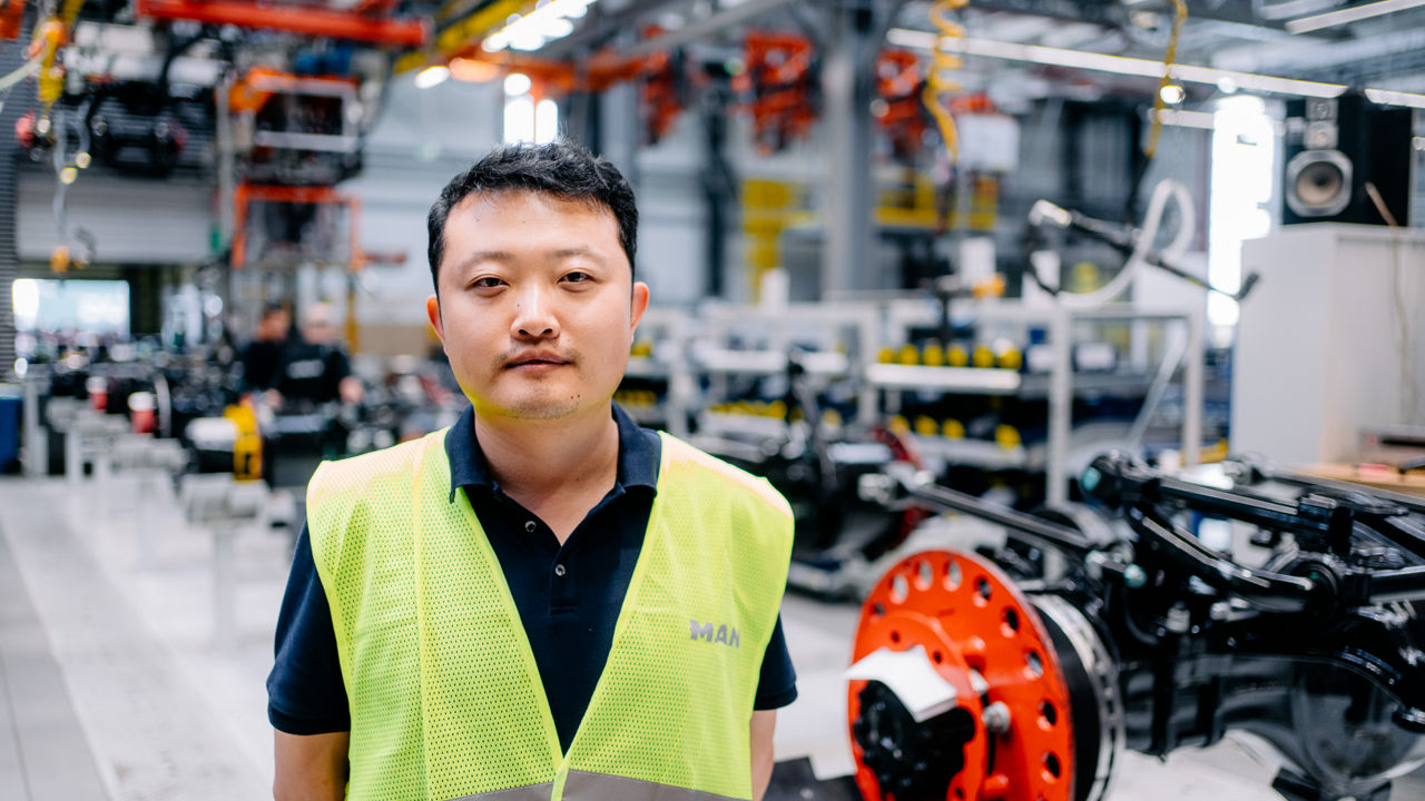 Ein Mann in Warnweste steht in einer Produktionshalle