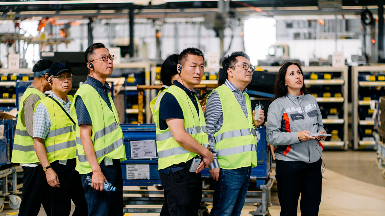 Ein Gruppe Menschen in Warnwesten schaut etwas an