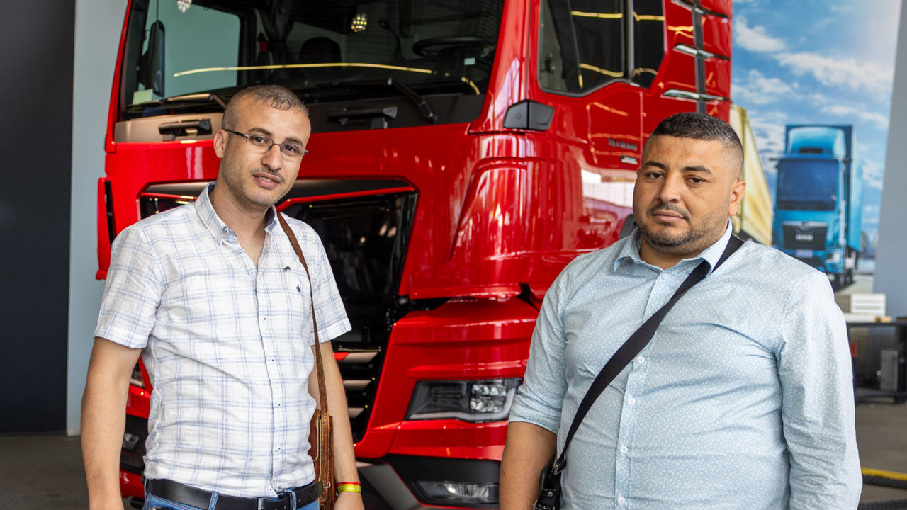 Two men standing in front of a red truck