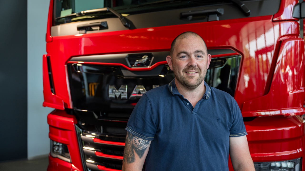 A man standing in front of a red truck