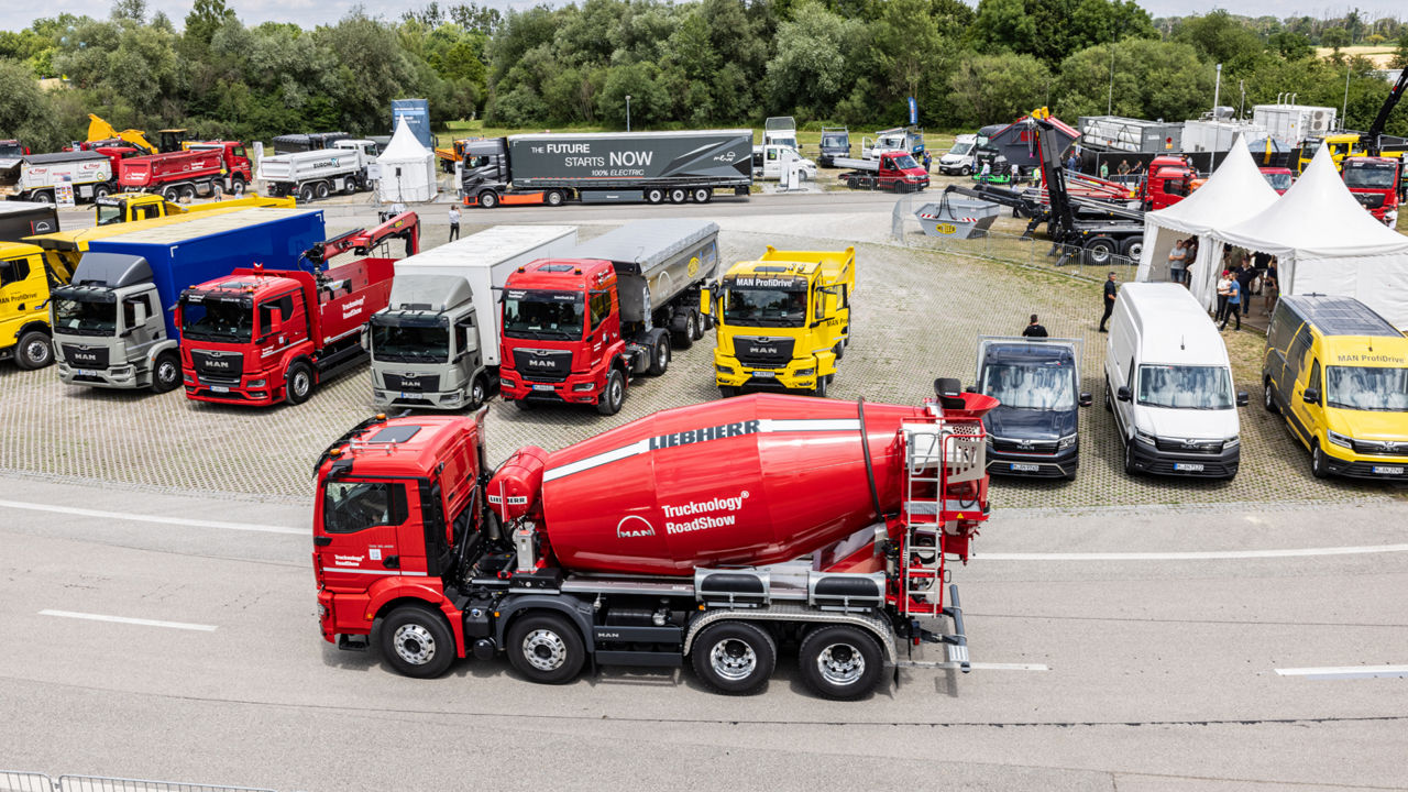 A concrete mixer driving in a car park with trucks