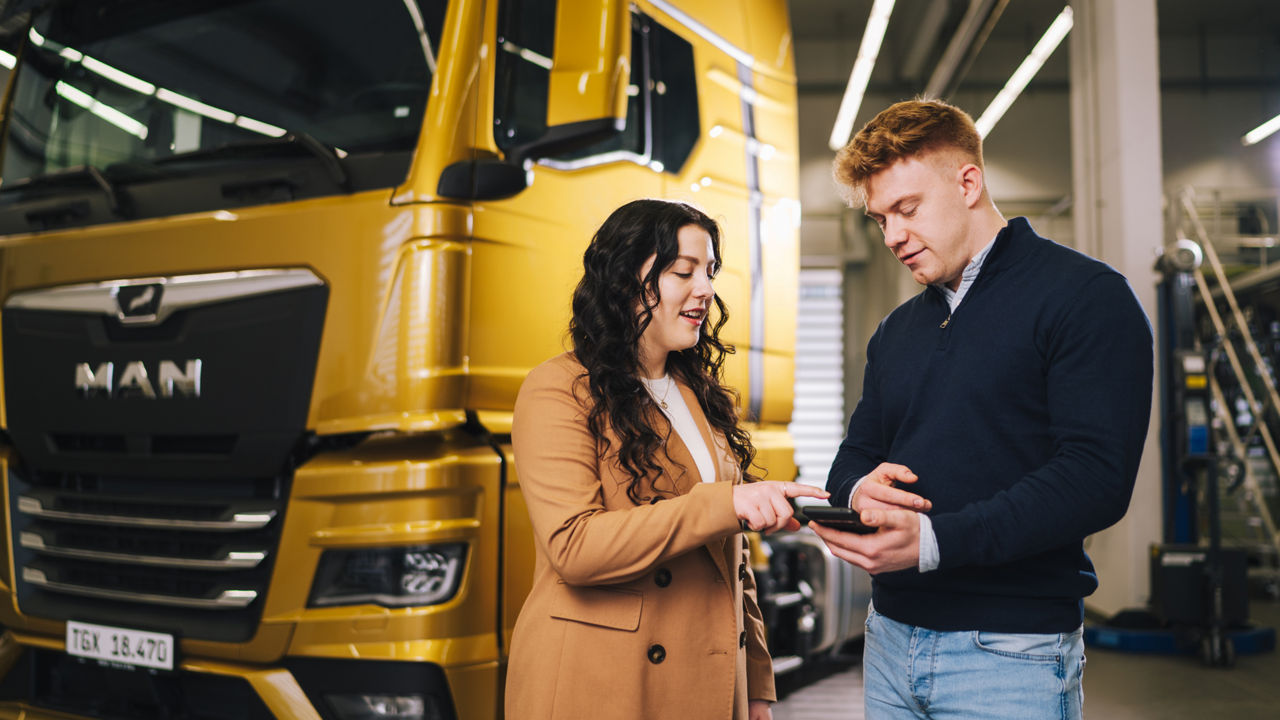 Two people standing in front of a truck talking