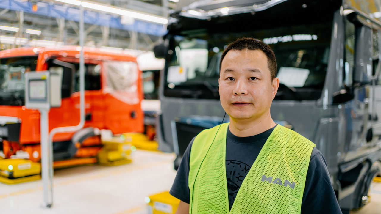 Ein Mann in einer Warnweste steht vor einem weißen Lkw