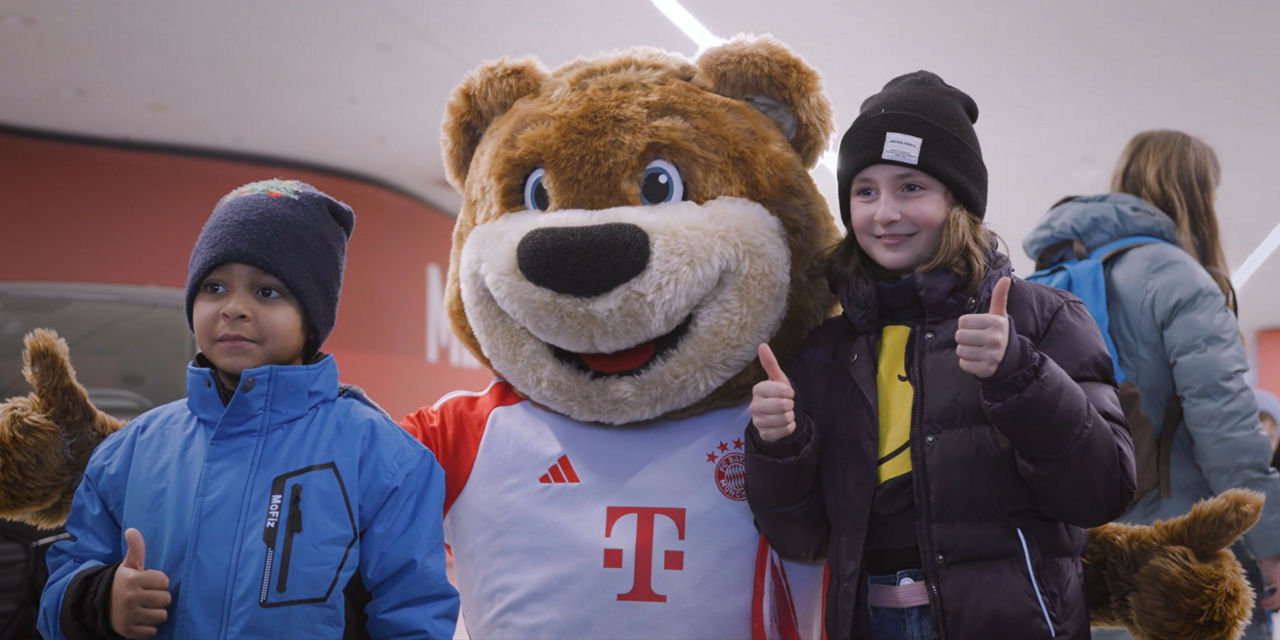 The FC Bayern mascot Bernie with two children