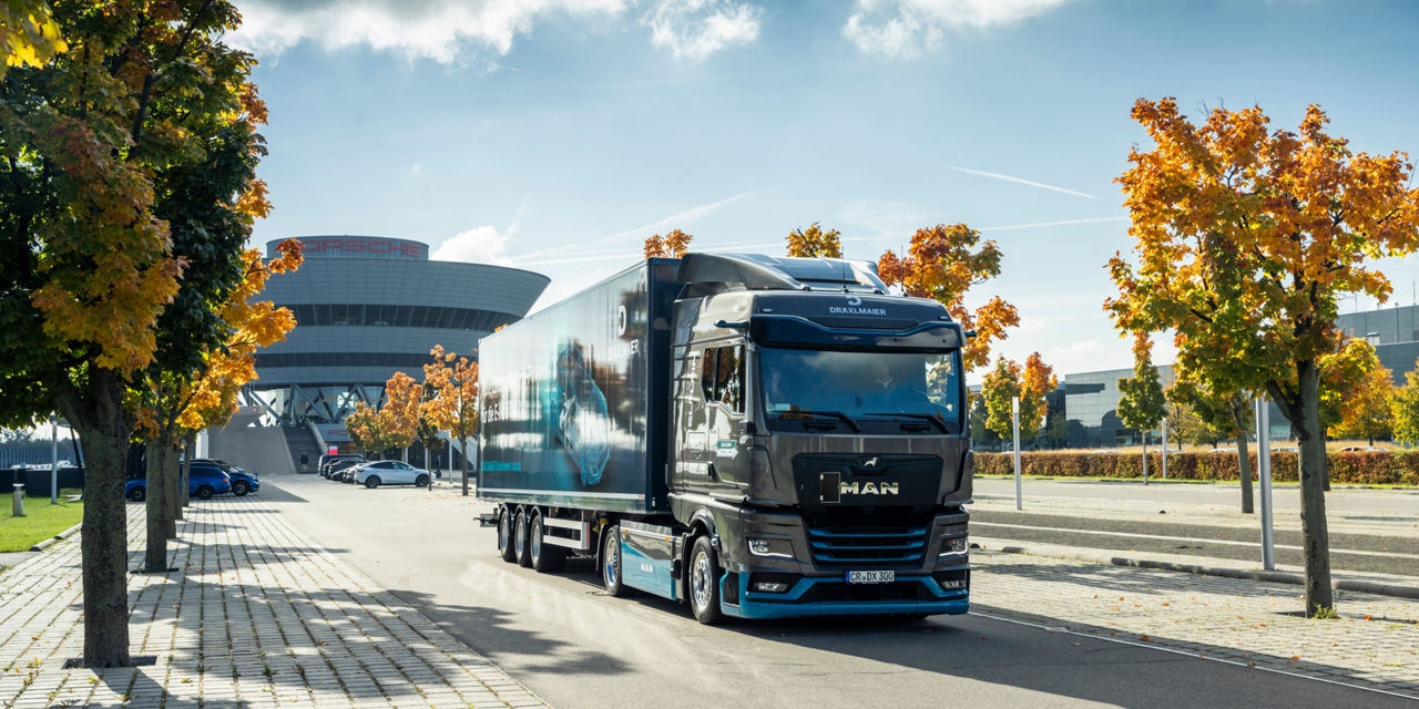A MAN eTGX is driving on a road with trees in autumn