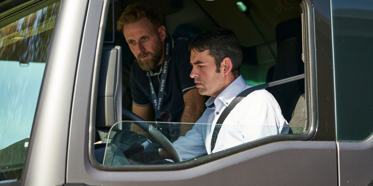 Ein Kunde probiert einen neuen Lkw aus, ein MAN-Mitarbeiter steht ihm beratend zur Seite