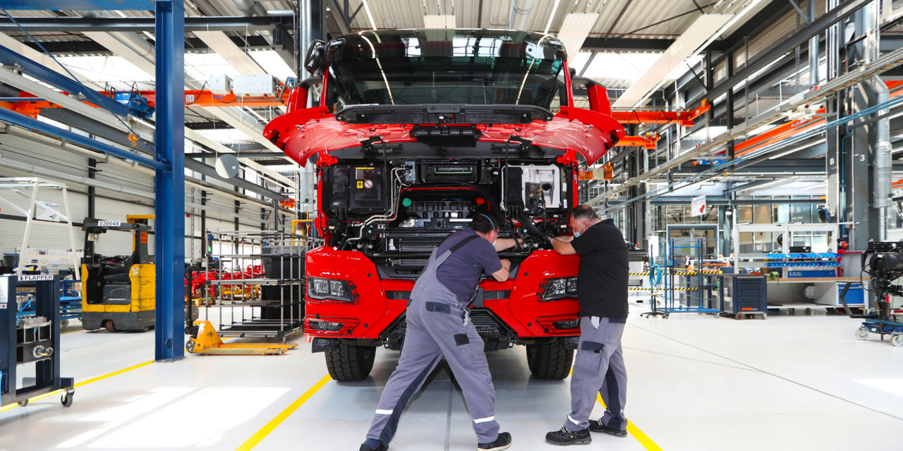 Zwei Mitarbeiter arbeiten an einem neuen Lkw von MAN