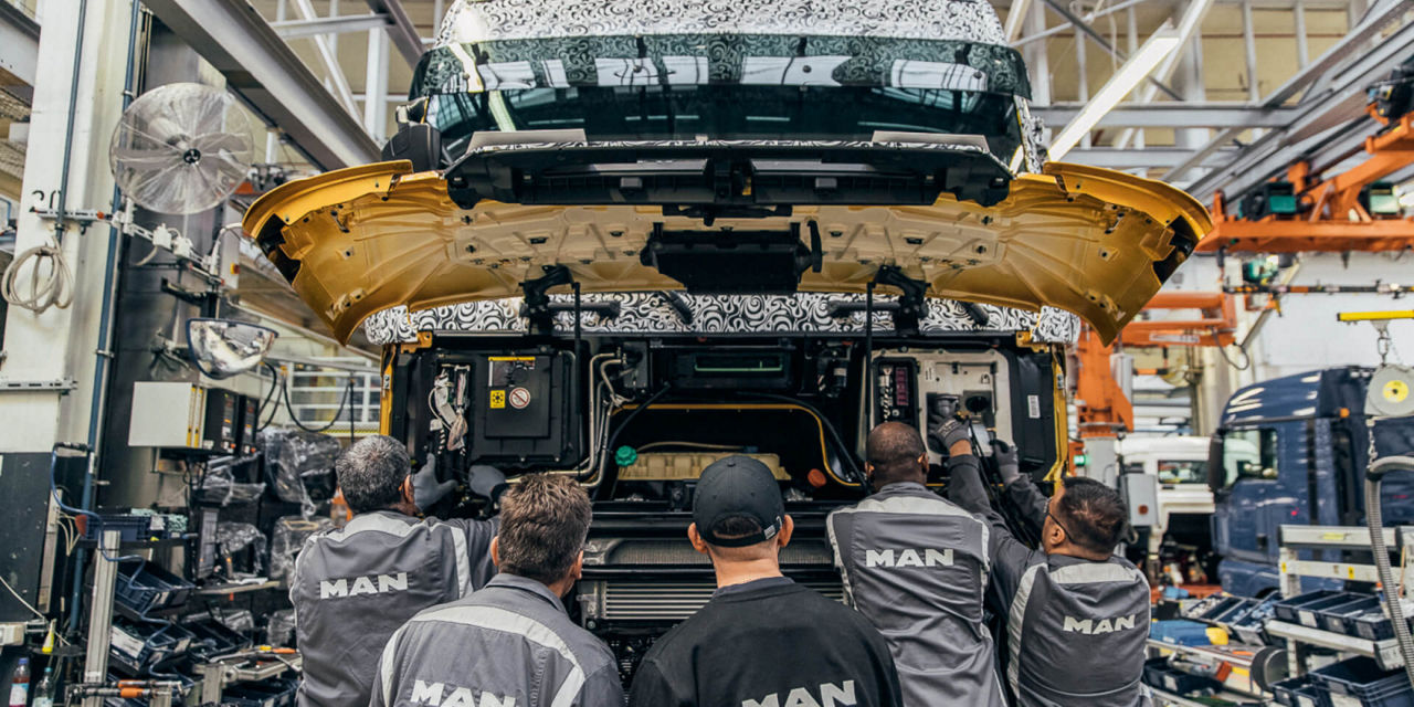 Workers assemble large parts on the front of the truck