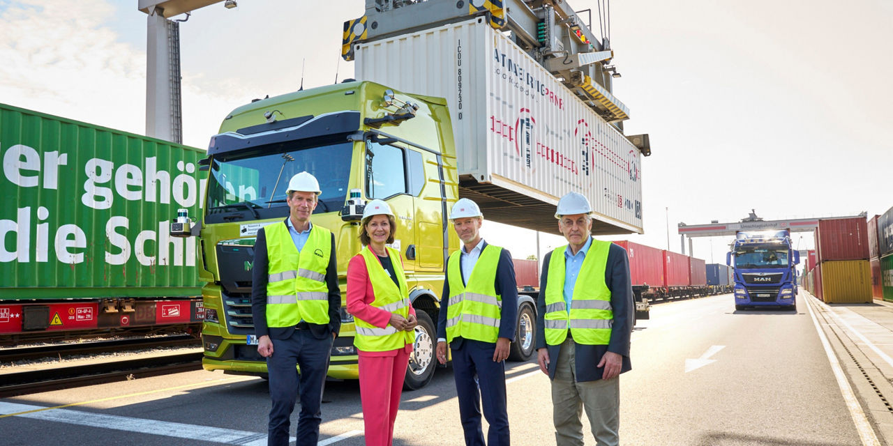 Four project participants stand in front of the MAN truck
