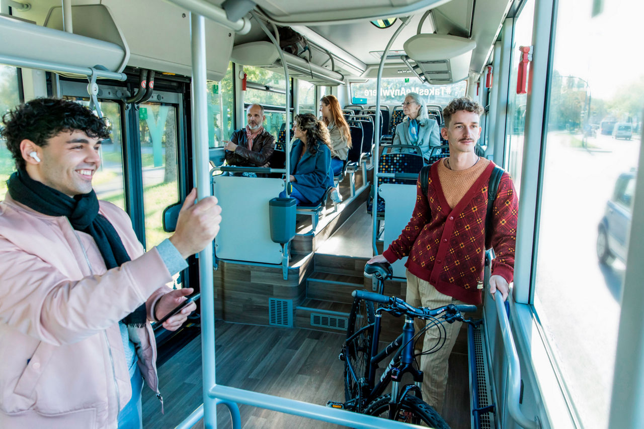 Sechs Passagiere sitzen und stehen im Inneren des MAN Lion’s Intercity LE. Ein Passagier hat ein Fahrrad im Bus dabei.