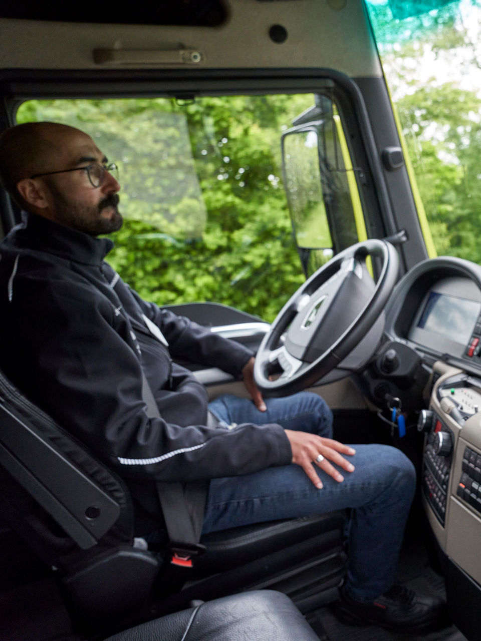 A man sits in a truck in front of screens