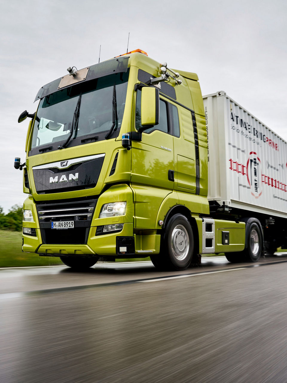 A green MAN truck driving on the road