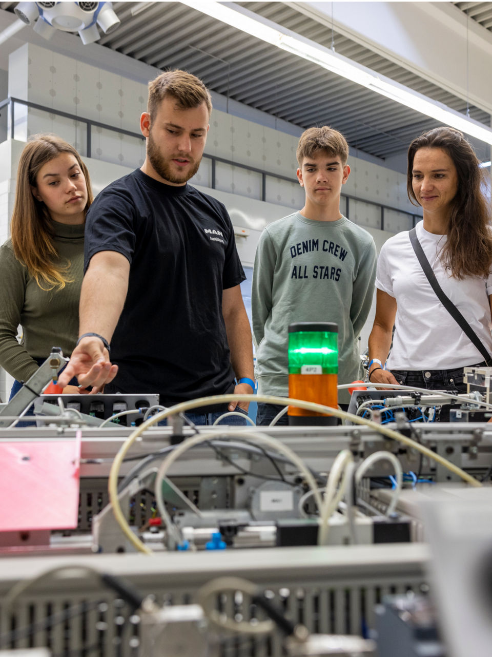 Jugendliche stehen vor einer Maschine mit vielen Kabeln