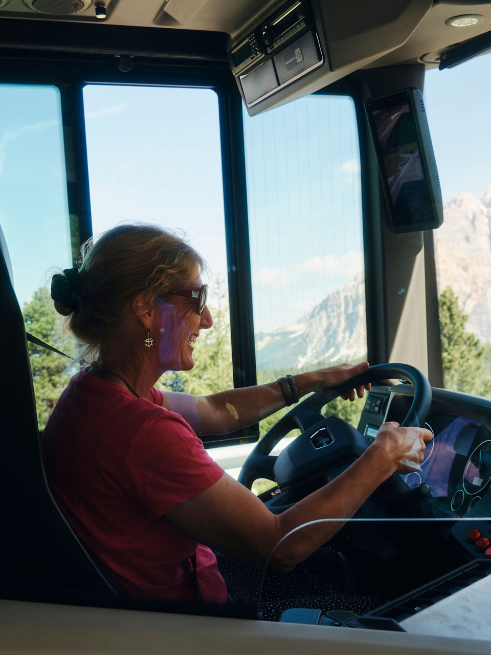 A woman sits at the wheel of a bus