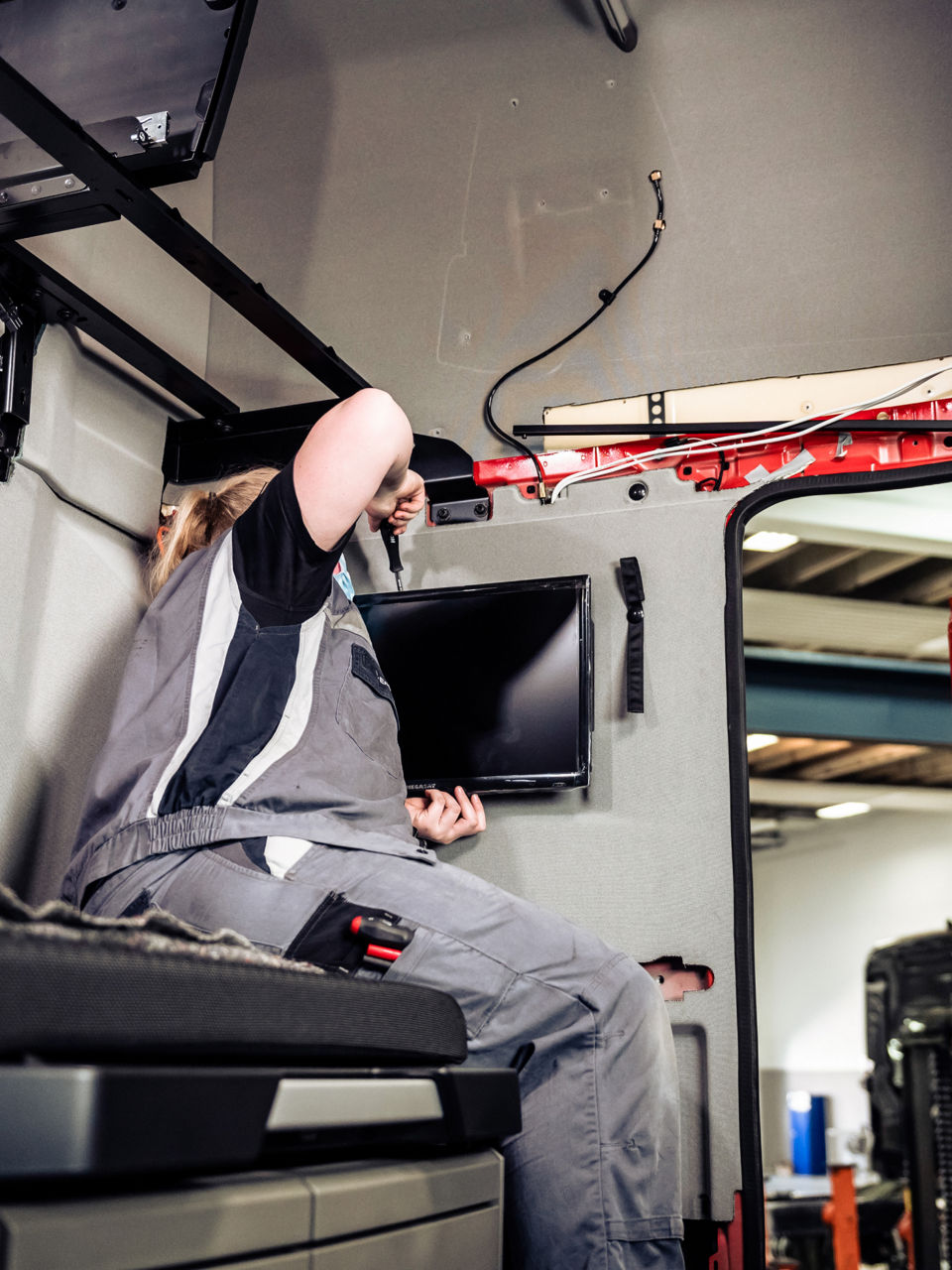 Eine Handwerkerin montiert einen Fernseher im Ruheraum