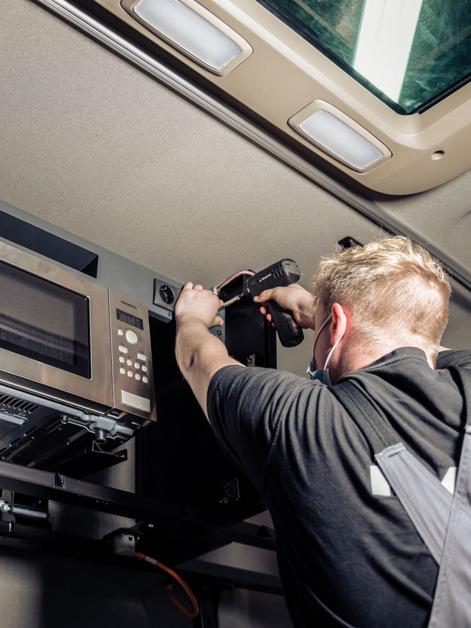 Der Meister montiert die Steckdosen rund um die Mikrowelle