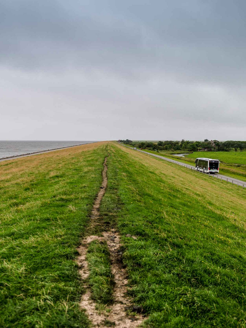 The sea dyke - the sea on one side, the road on the other and the bus on it