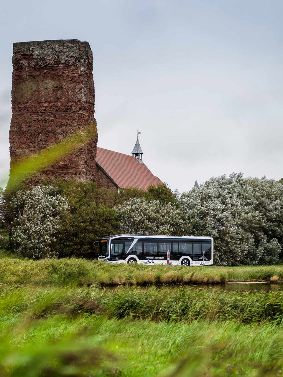 MAN Lion's City E and the old church with the ruins of the tower
