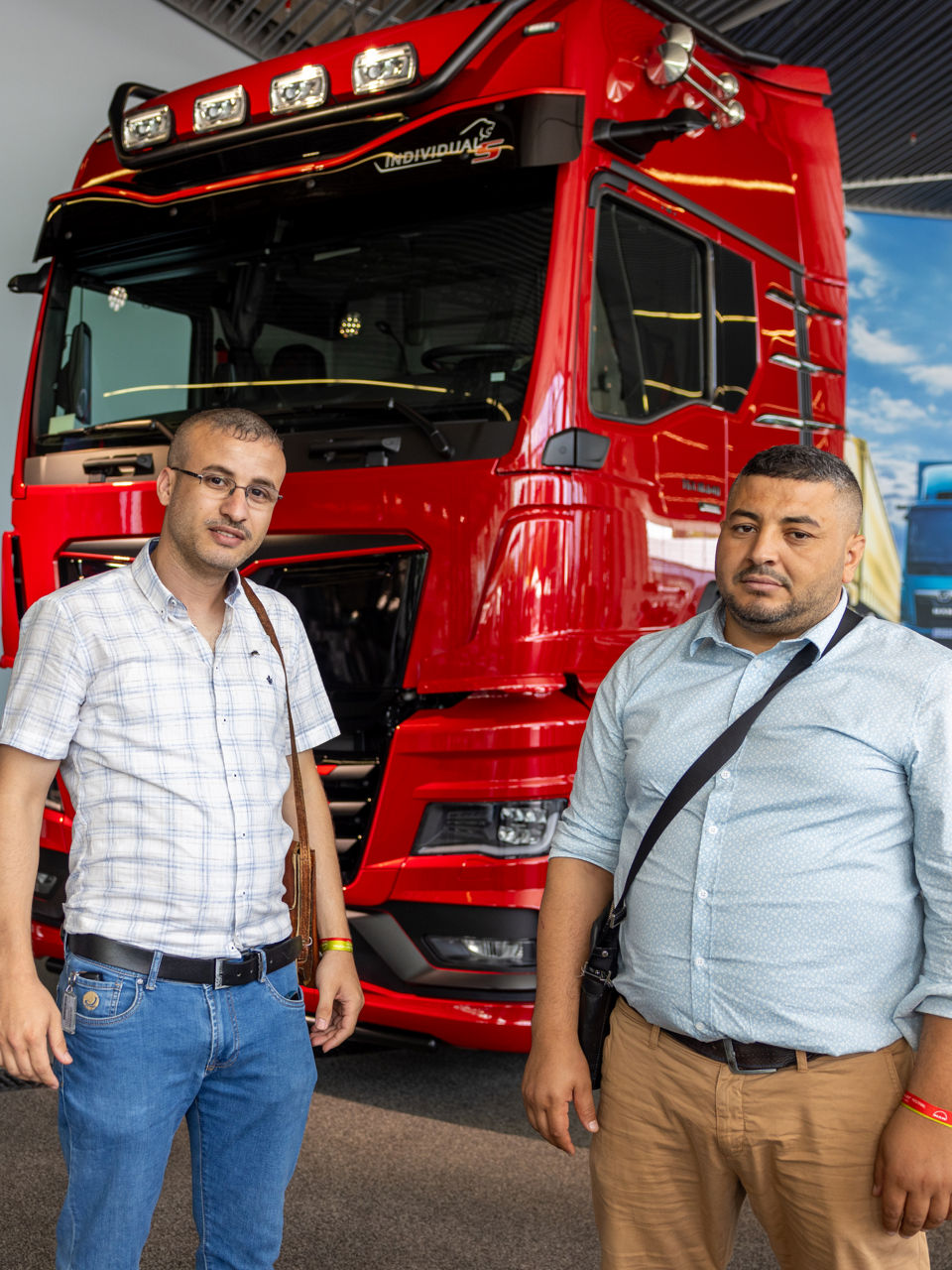 Two men standing in front of a red truck