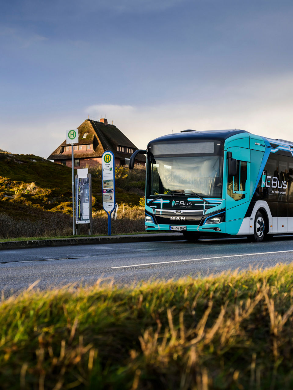 The Model 18 E bus is parked at a bus stop on a country road