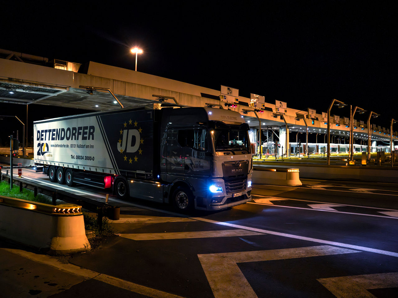 Ein MAN eTGX an einer Mautstelle bei Nacht.