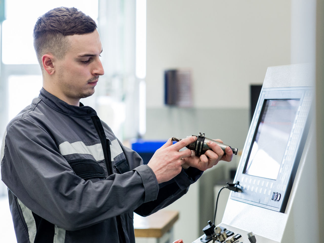 Ein junger Mann arbeitet mit einem Werkzeug und einem Bildschirm