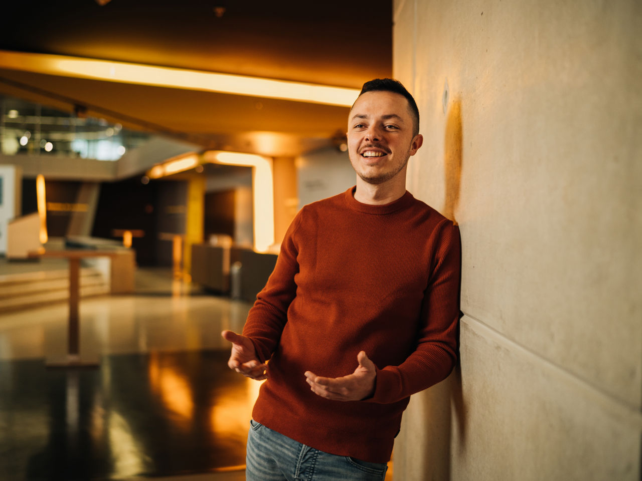 A young man is leaning against a wall