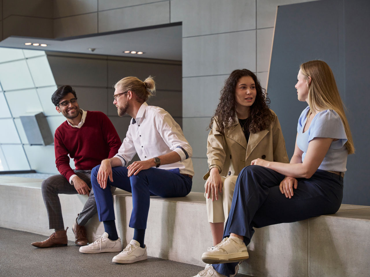 Two men and two women are sitting on a step and talking.