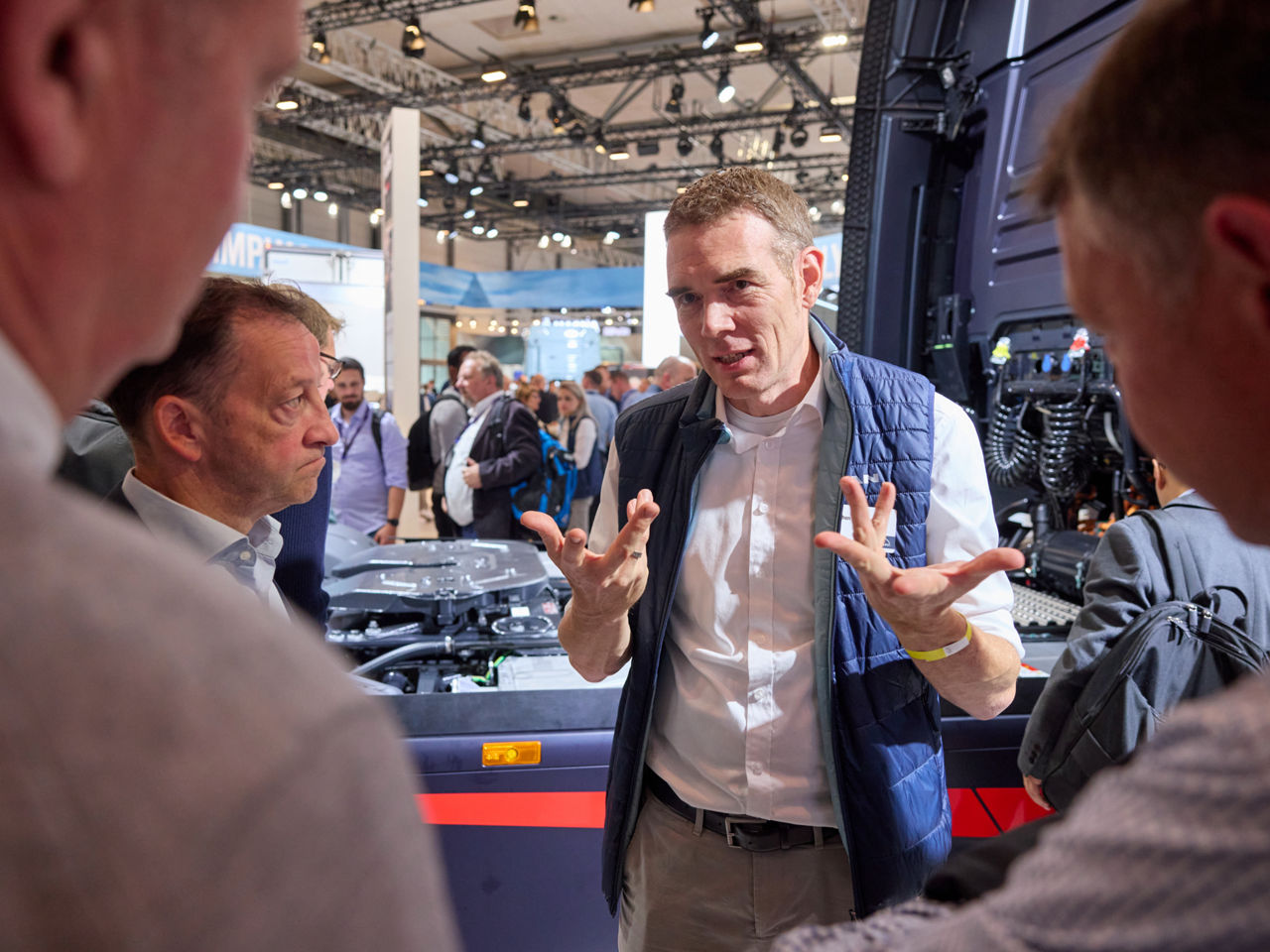 Ein Mann steht vor einem Lkw und gestikuliert, während er spricht.