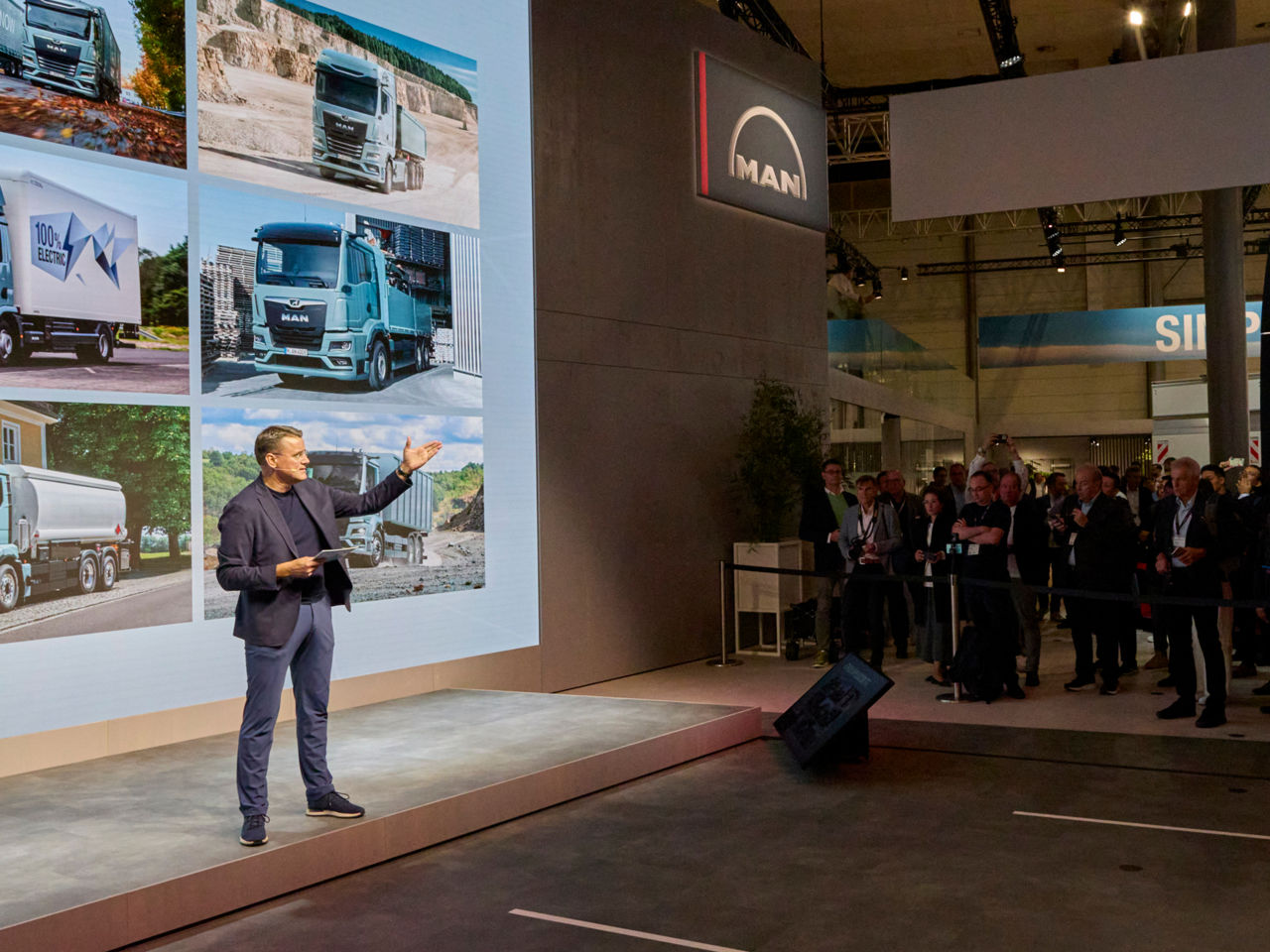 Alexander Vlaskamp steht vor einer großen Leinwand auf einer Bühne und spricht zu einer stehenden Menschenmenge