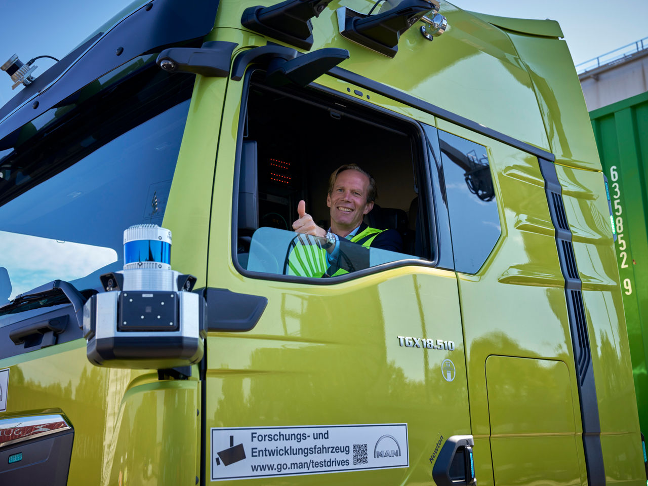 A man sits in the MAN truck and smiles contentedly. 