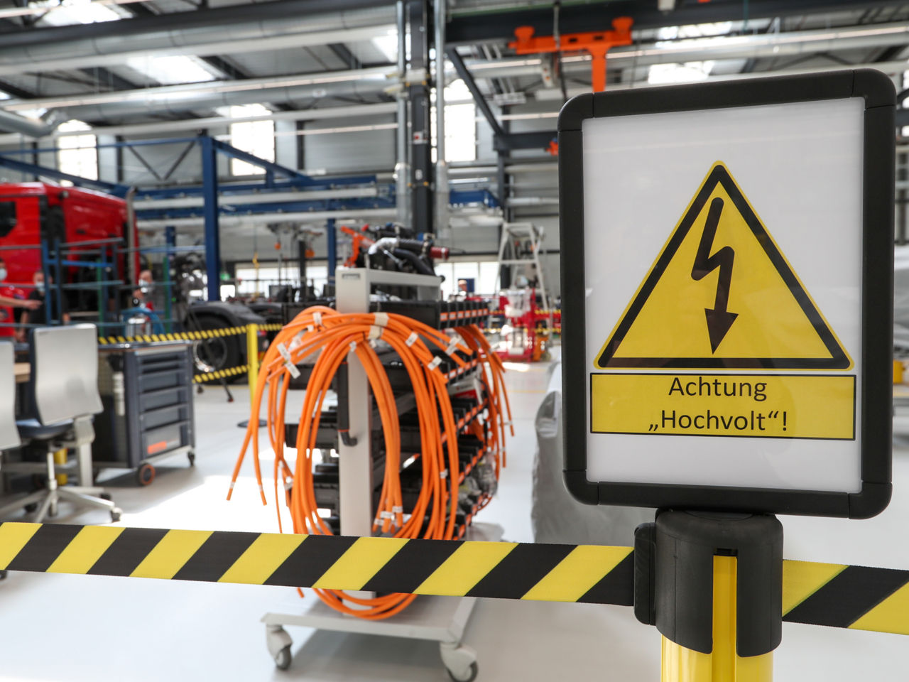 Ein Schild, welches vor Hochspannung warnt, vor einem abgesperrten Fabrikbereich