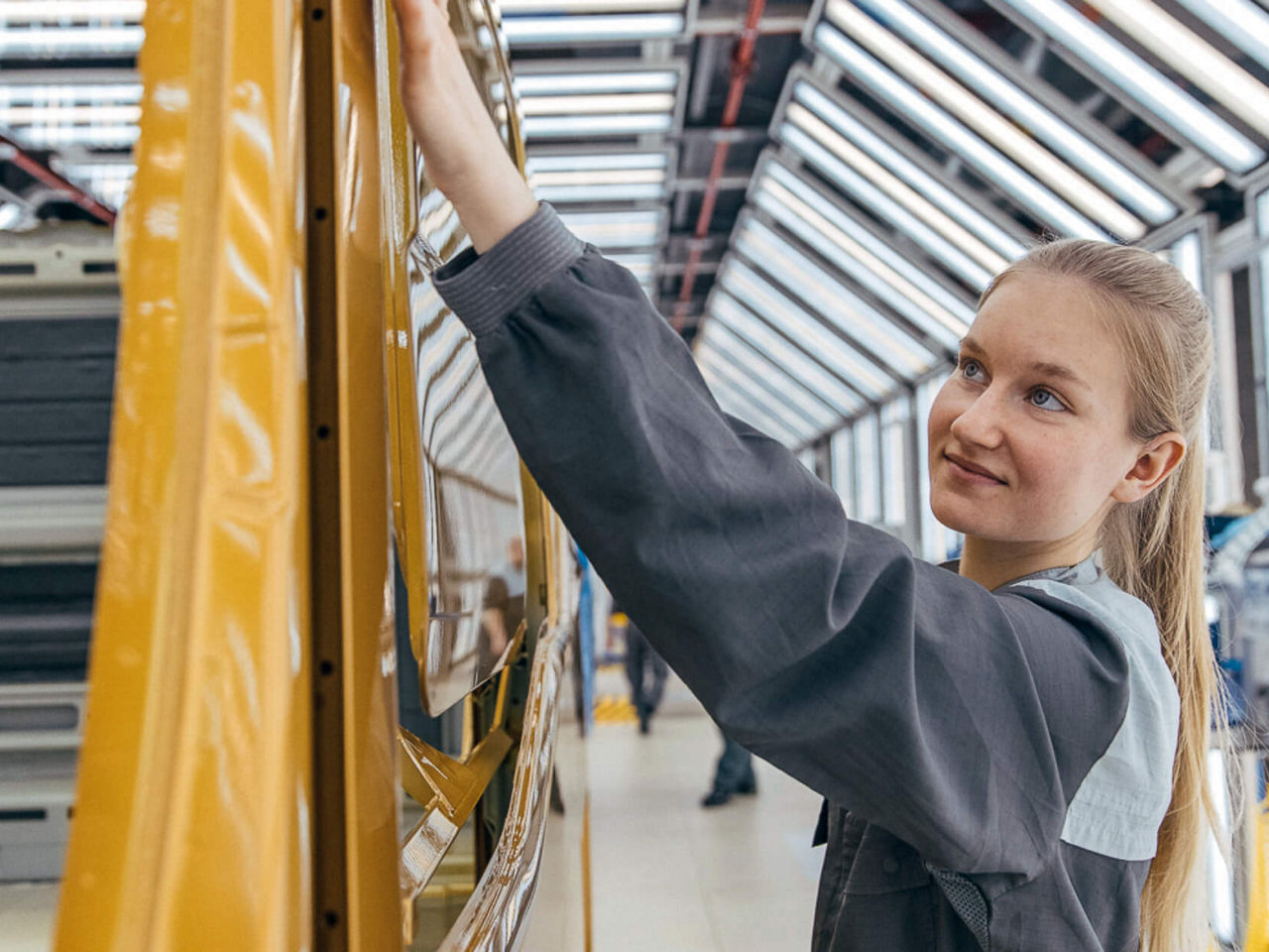 Eine junge Frau arbeitet an einer Lkw-Karrosserie