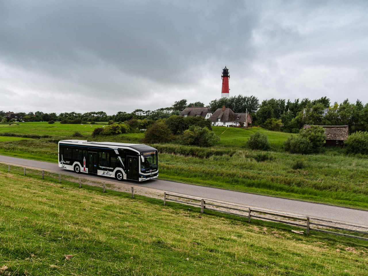Photo of white MAN Lion's City 12 E bus with lighthouse in the background