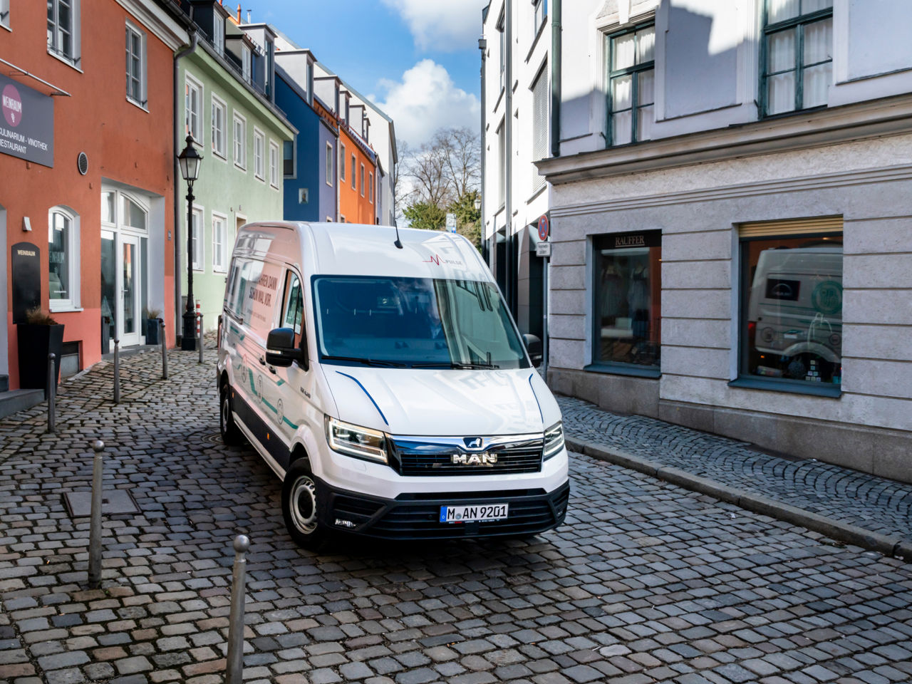 A white MAN van parked on a small street in an old town
