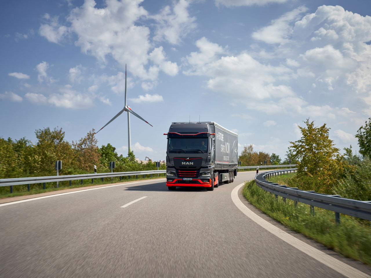 Der neue E-Lkw von MAN mit einem Windrad im Hintergrund