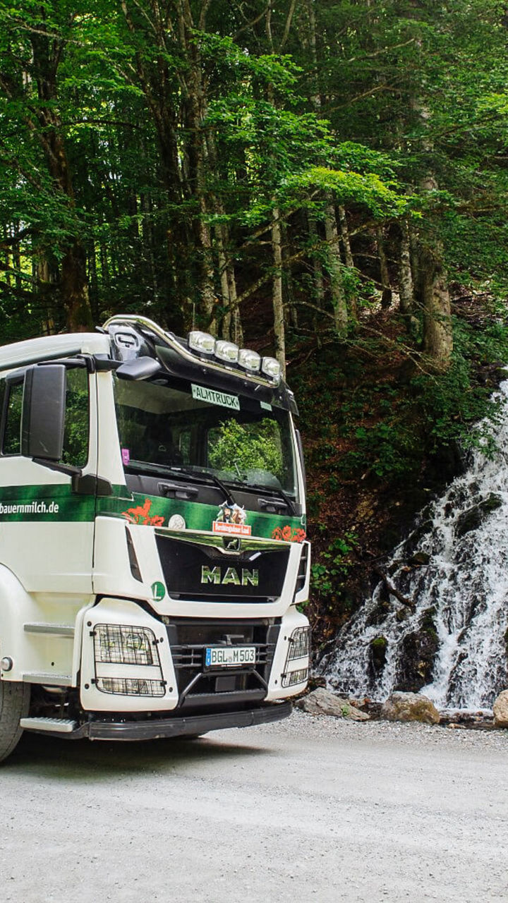 Almtruck fährt an einem Wasserfall vorbei